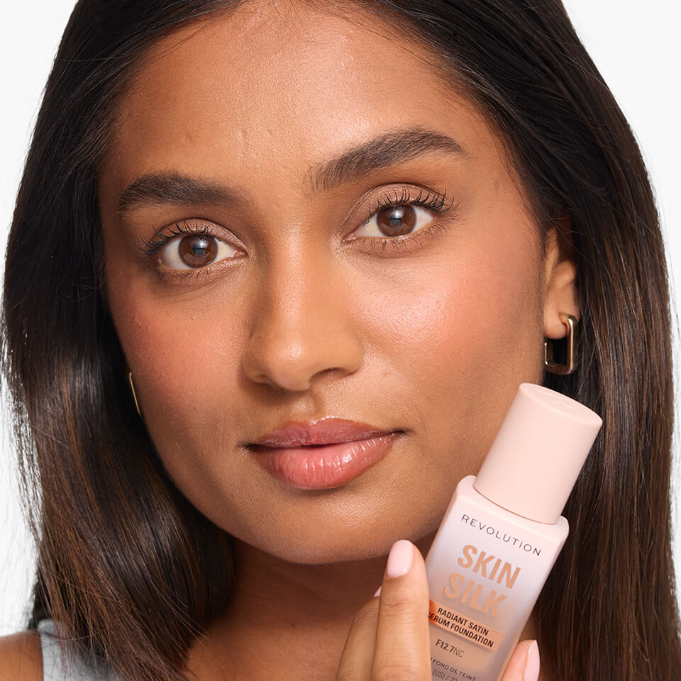 A photo of a model holding the Revolution Skin Silk Serum Foundation